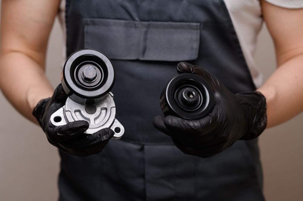 A man is holding two belt tensioners in his hands.