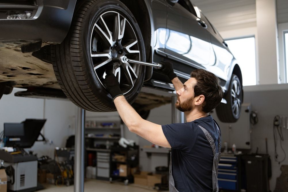 A man is changing a tire on a car in a garage.