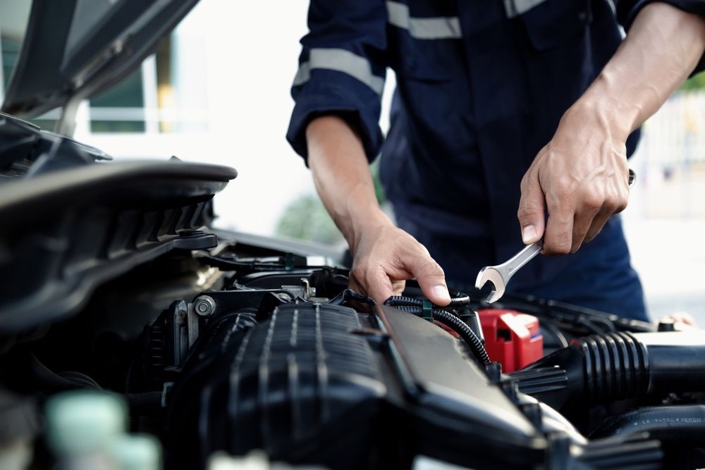 A man is working on the engine of a car with a wrench.
