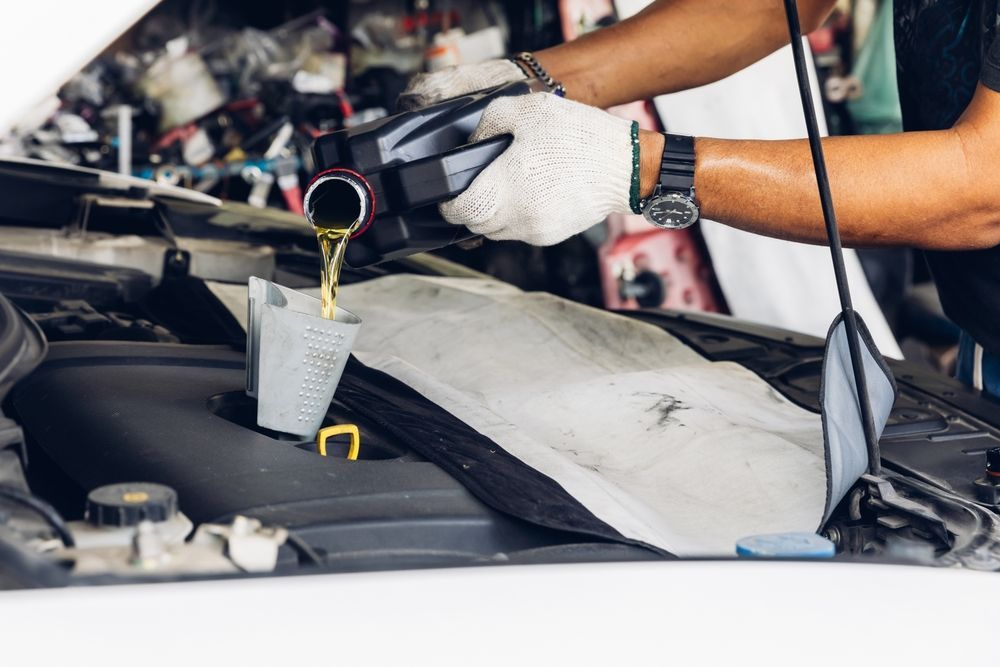 A man is pouring oil into a car engine.