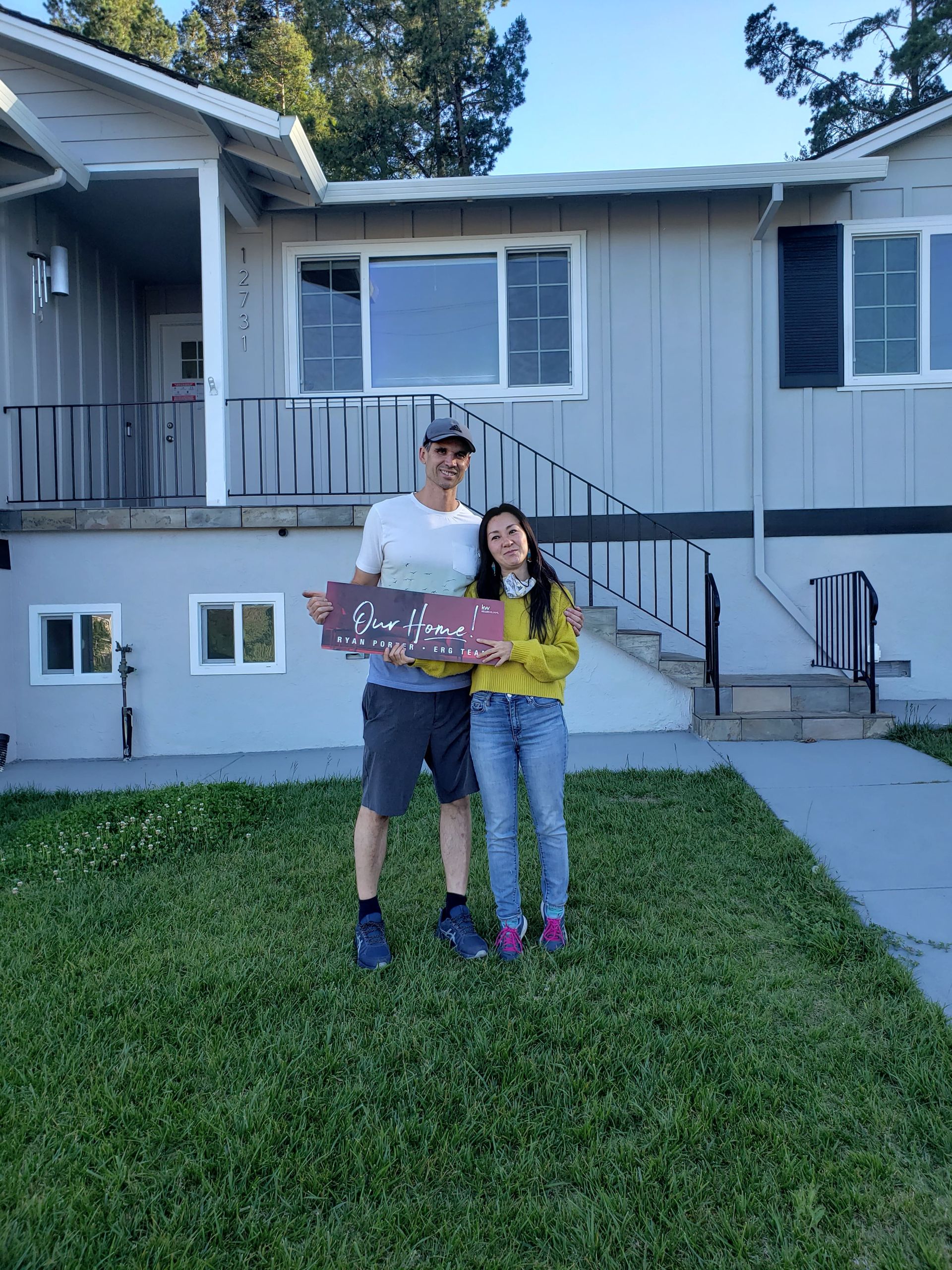 Clients of Eloise Real Estate Group are standing in front of a house holding a sign.