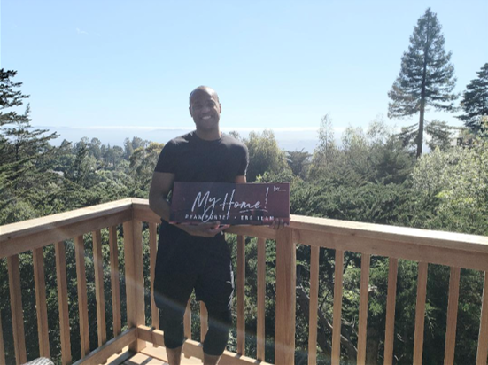 A client of Eloise Real Estate Group is standing on a balcony holding a sign that says `` my home ''.