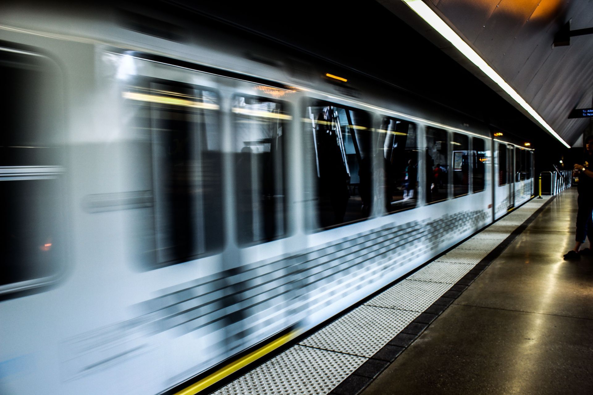 Blurred white subway train speeding through an underground station platform
