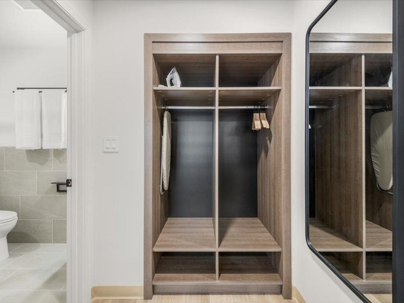 Open closet in a bathroom with shelves, hanging space, and mirrored sliding doors.