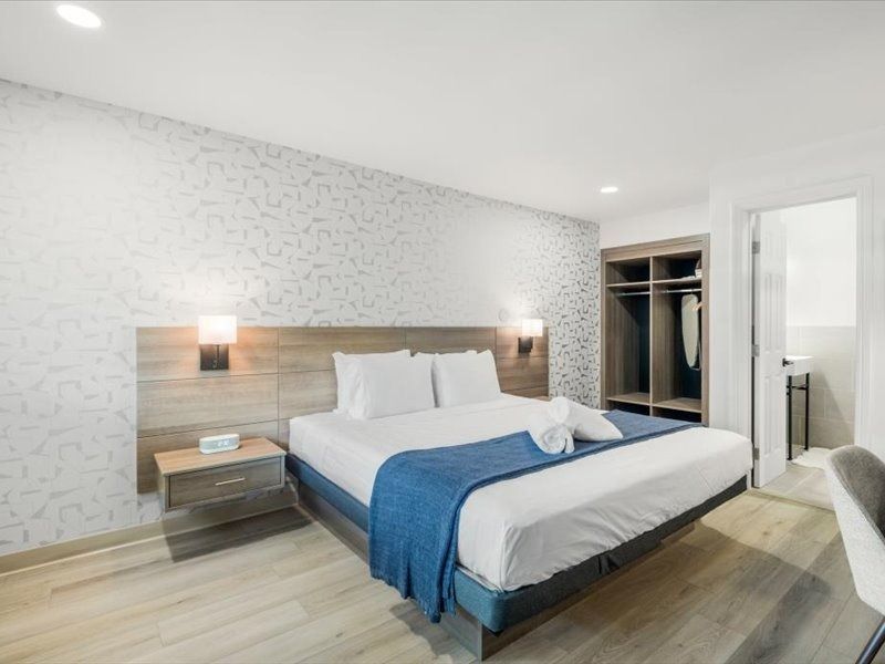 Modern bedroom with a king bed, blue throw, nightstands, and open closet doors