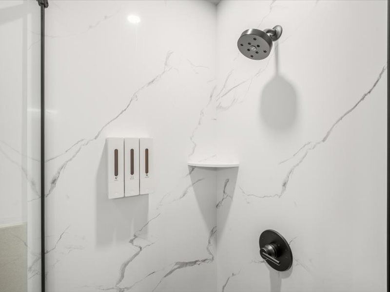 Modern shower with white marble tile, two showerheads, and built-in soap shelves