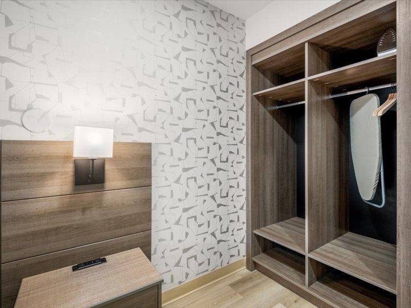 Modern bedroom with wood wardrobe, bedside lamp, and patterned wallpaper