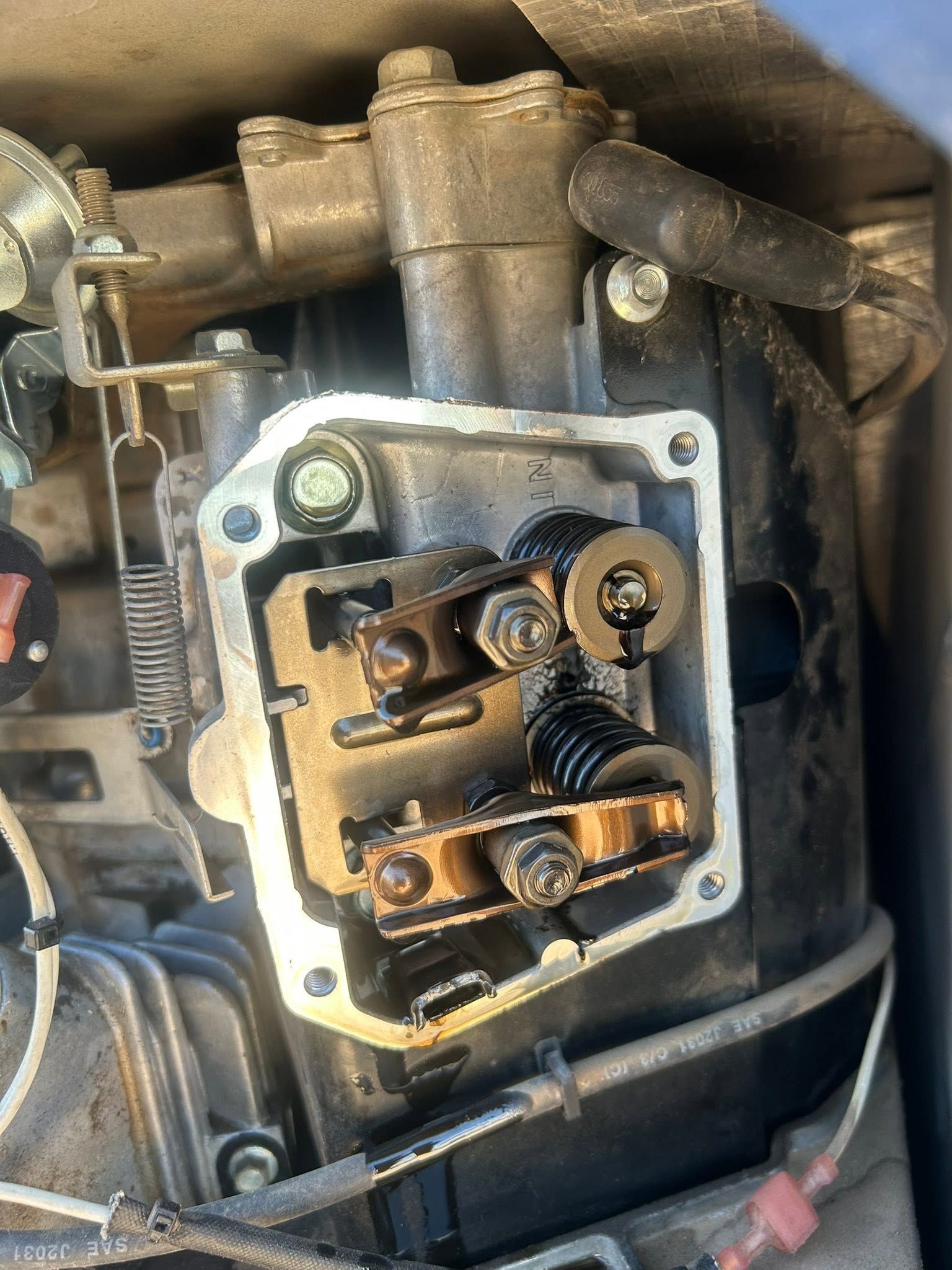 Close-up of an exposed mechanical engine component with metal linkage, springs, and bolts. | OverDrive Auto Service