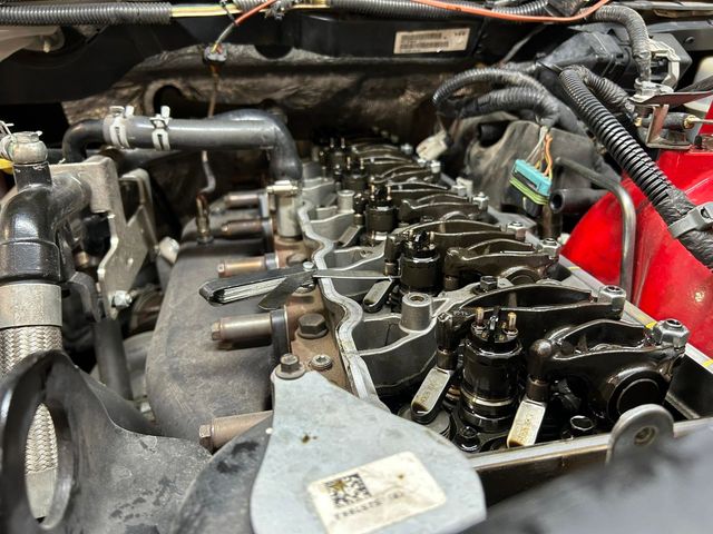 Car engine with valve cover removed, exposing black engine components and wiring in the engine bay. | OverDrive Auto Service
