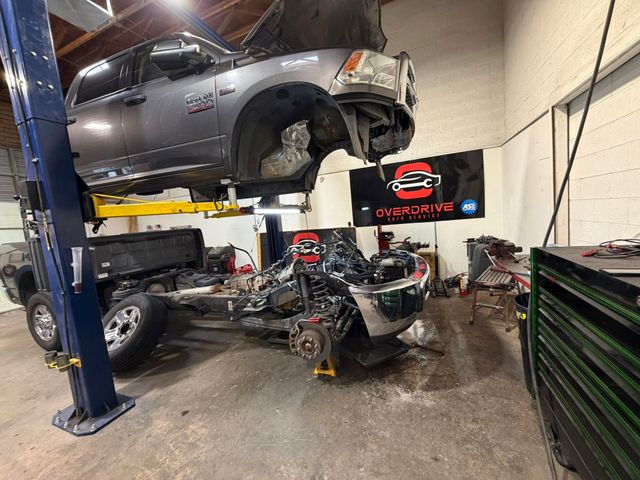 Auto repair shop with a gray truck on a lift and a disassembled engine on the floor | OverDrive Auto Service