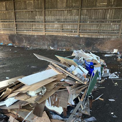 A pile of junk is sitting on the ground in front of a building.