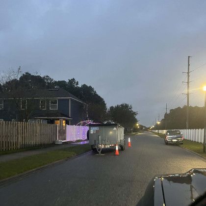 A trailer is parked on the side of the road in front of a house.