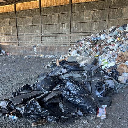 A pile of trash is sitting on the ground in front of a building.