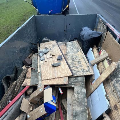 The back of a dumpster filled with wood and boxes