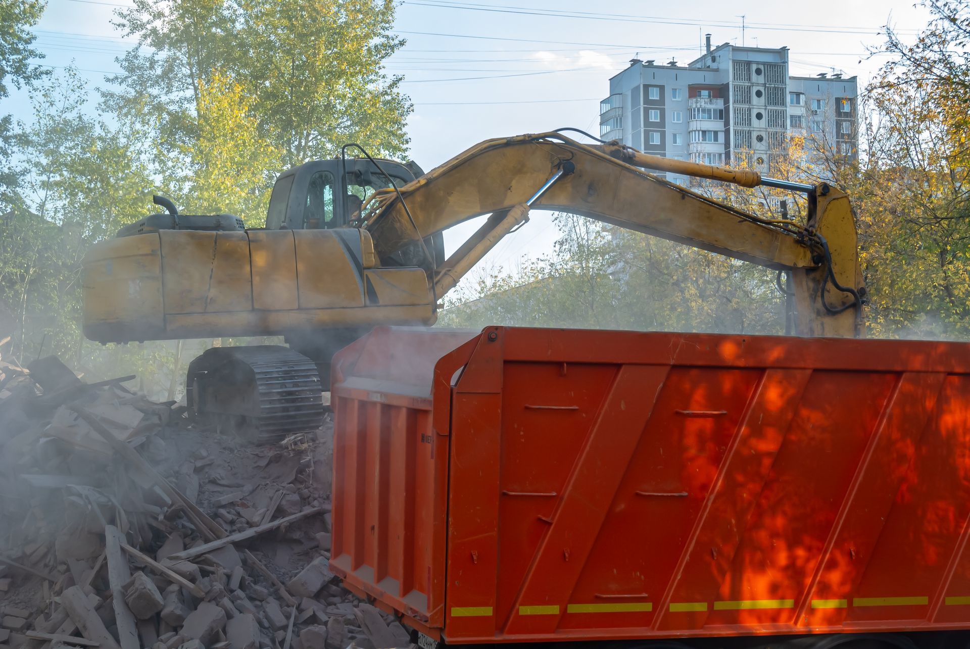 A bulldozer is loading dirt into a dump truck.