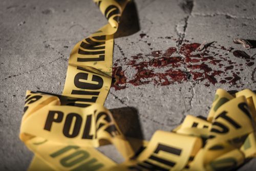 Yellow police tape around a bloodstain on concrete ground