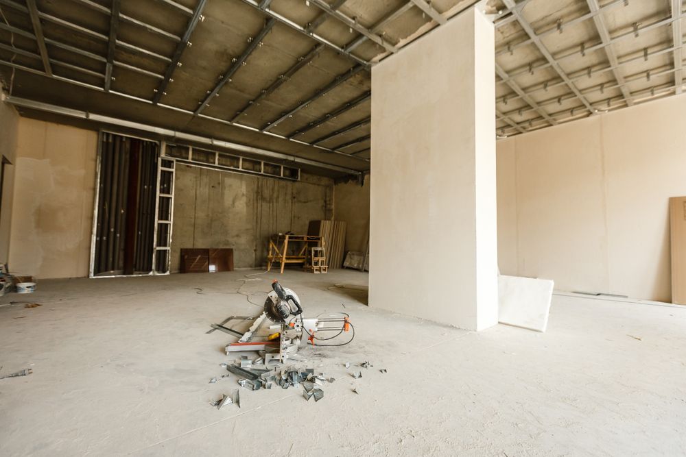 Empty unfinished interior with exposed ceiling, drywall partitions, and construction debris on the floor