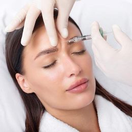 A woman is getting cosmetic treatments such as a botox injection in her forehead
