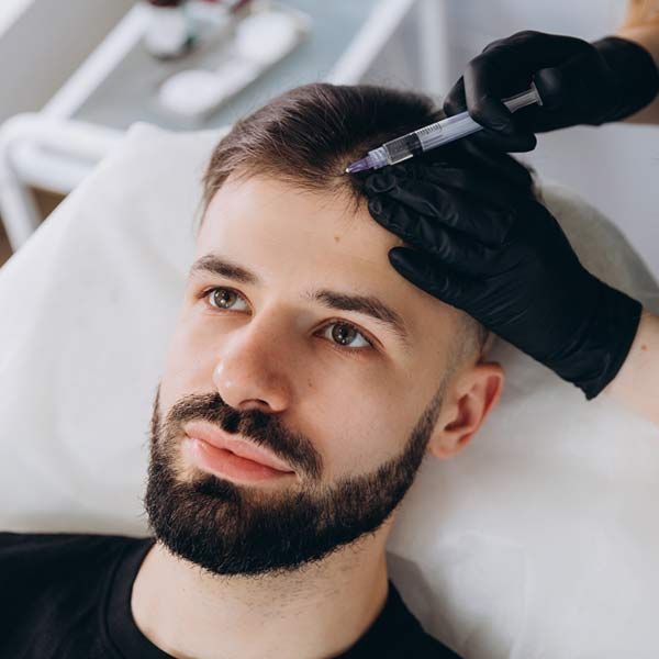 A man with a beard is getting hair regrowth therapy