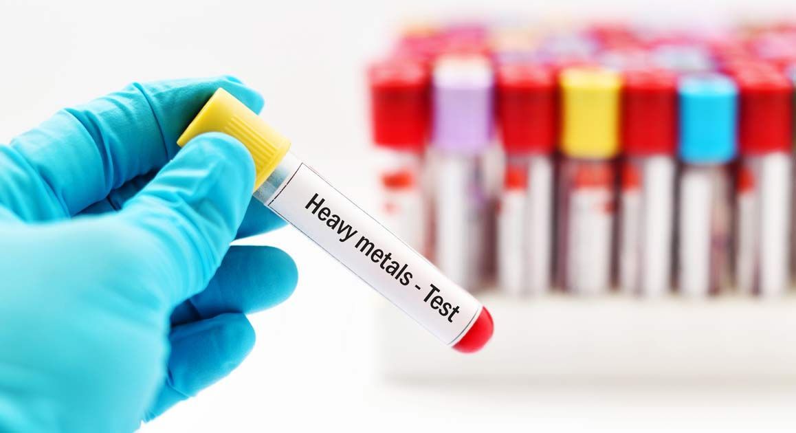 A gloved hand holding a test tube labeled Heavy Metal Detox NJ - Dr. Kamal Kalsi
