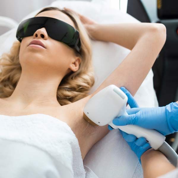 A woman wearing sunglasses is getting her armpit Laser Hair Removal