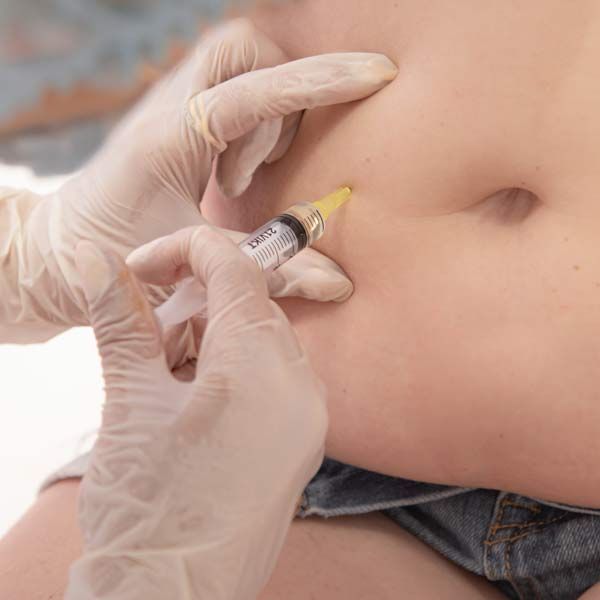 A person is getting an injection in their stomach for Peptide Therapy