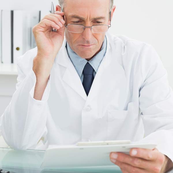 Conventional Doctor in white coat reading a lab report for a PCOS patient