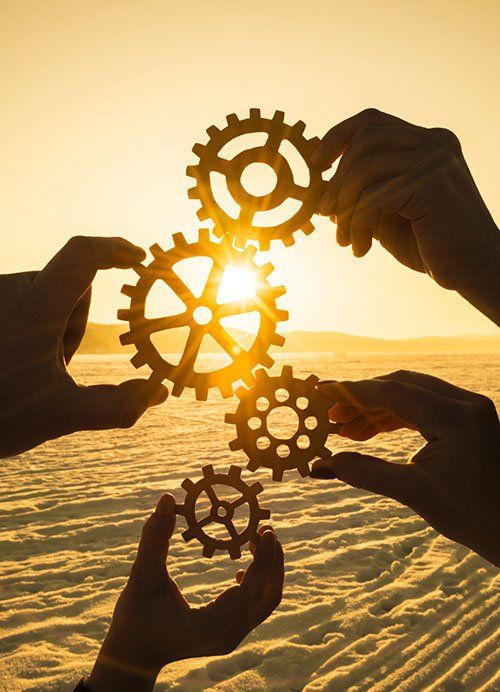 A group of people are holding gears in their hands in front of the sun