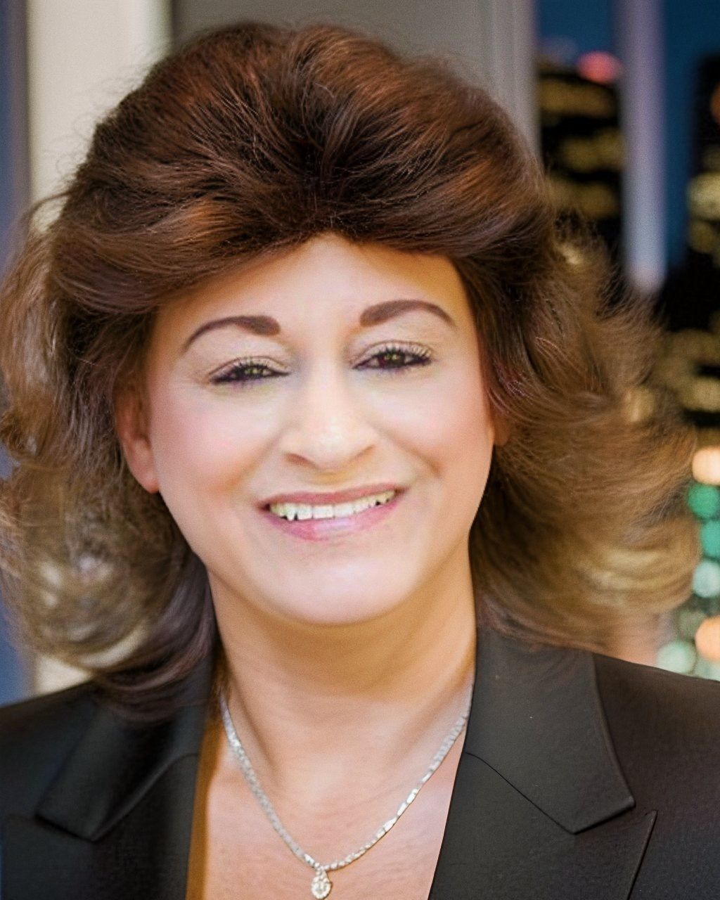 A woman wearing a wig and a necklace smiles for the camera