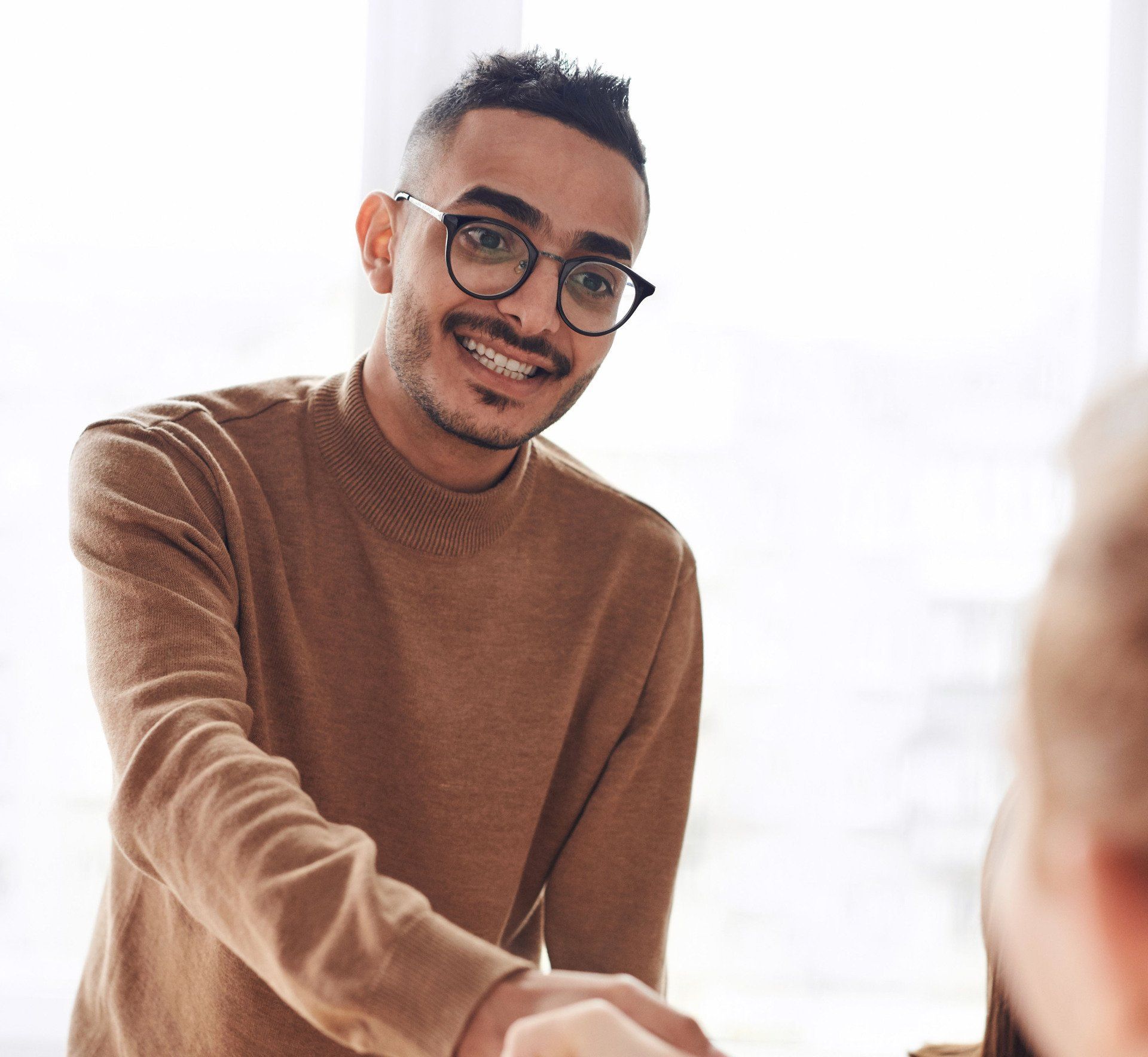 A man wearing glasses is shaking hands with another man