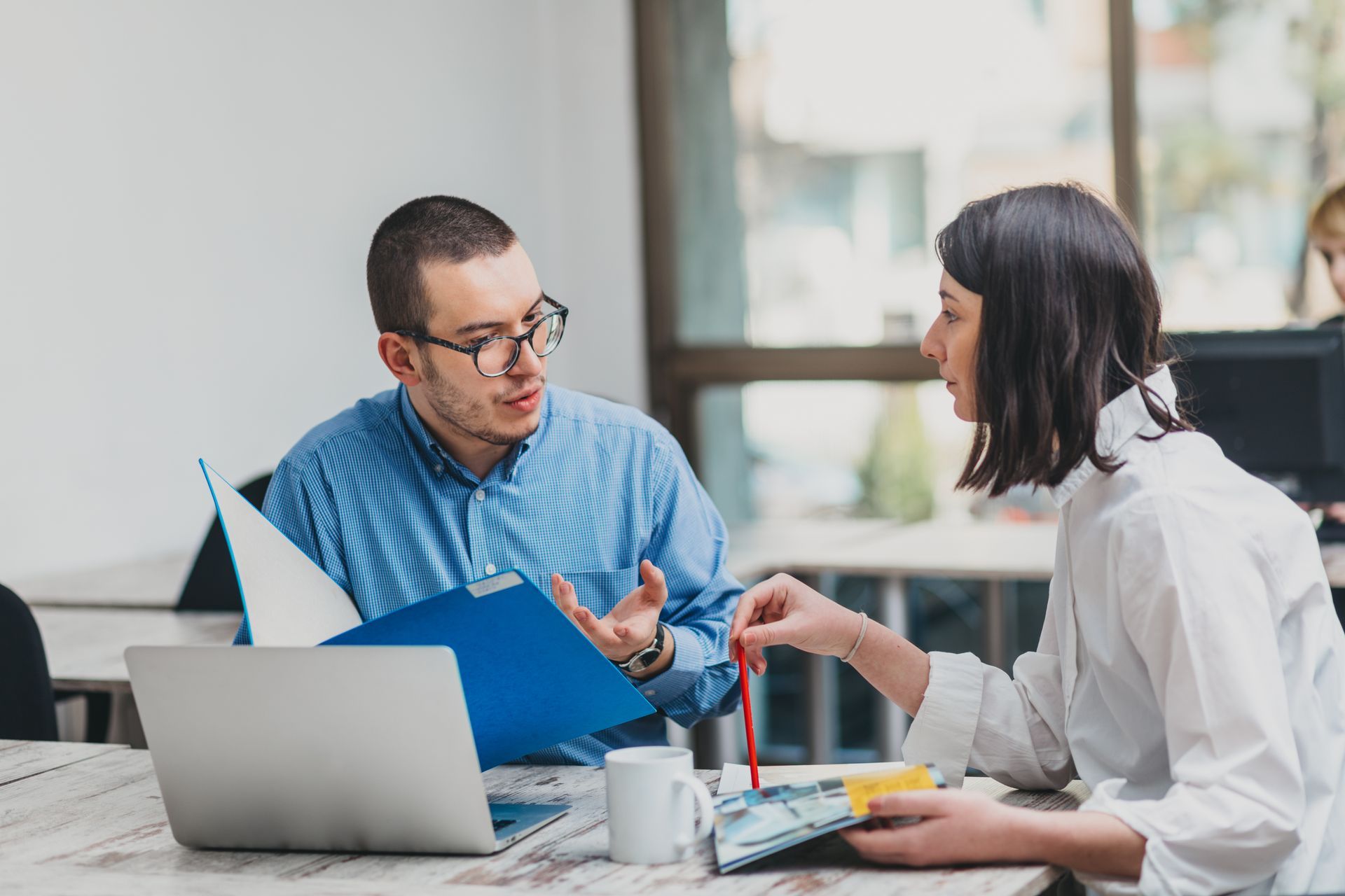 an employee benefits broker sitting next to a colleague discussing benefits programs