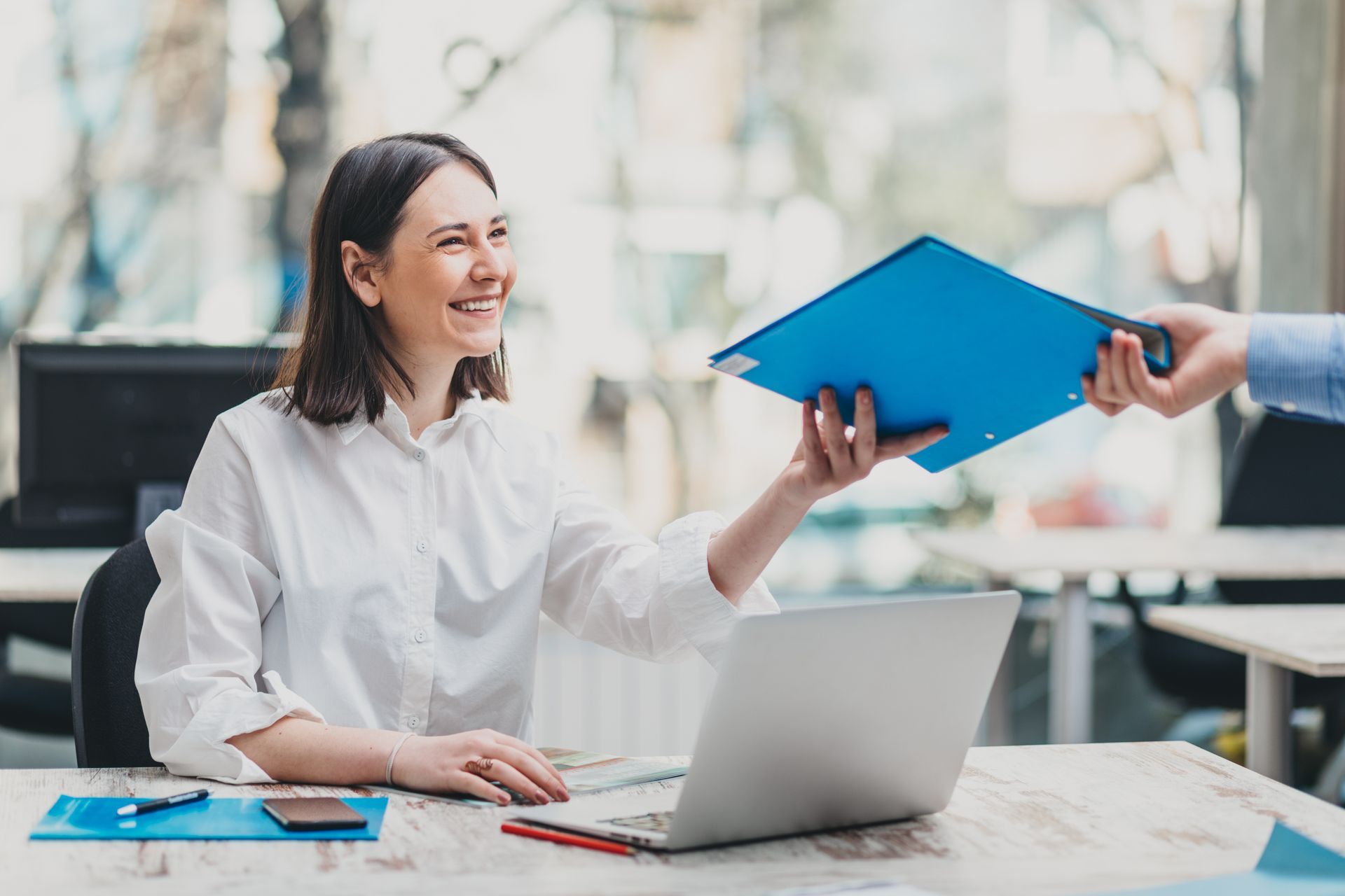an employee benefits broker sitting at a desk with a laptop and a blue folder