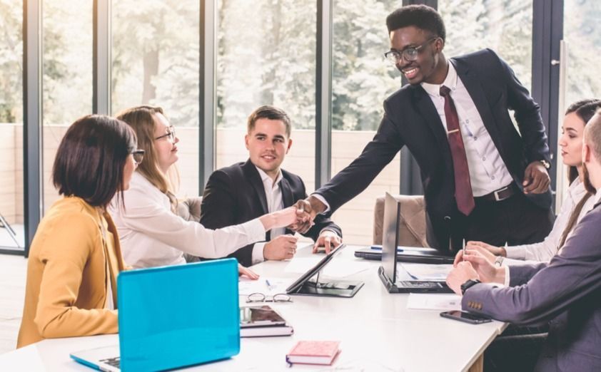 Team members shake hands during a buy sell agreement meeting