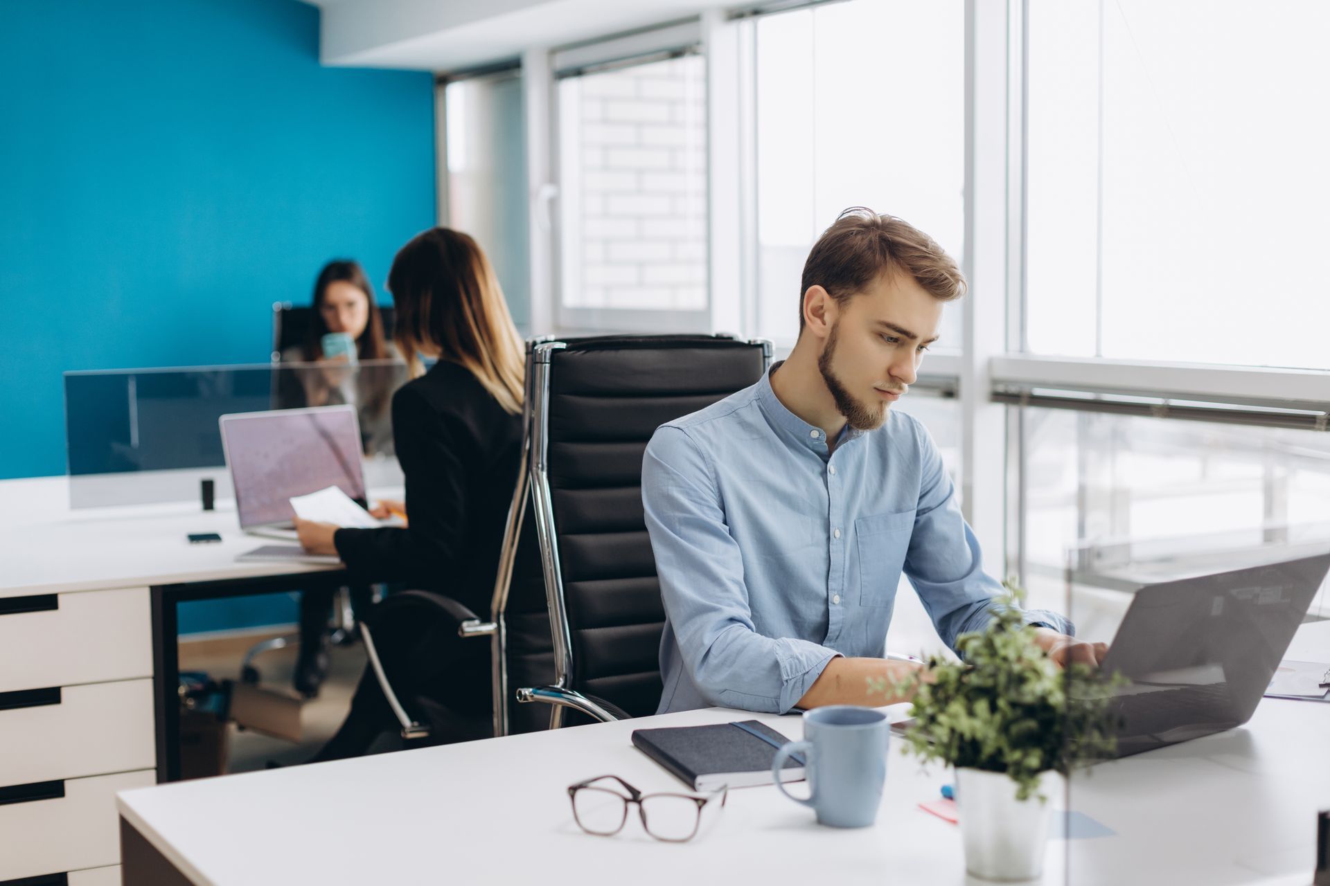 a man is sitting at a desk in an office using a laptop computer looking at his employee health benefit options 