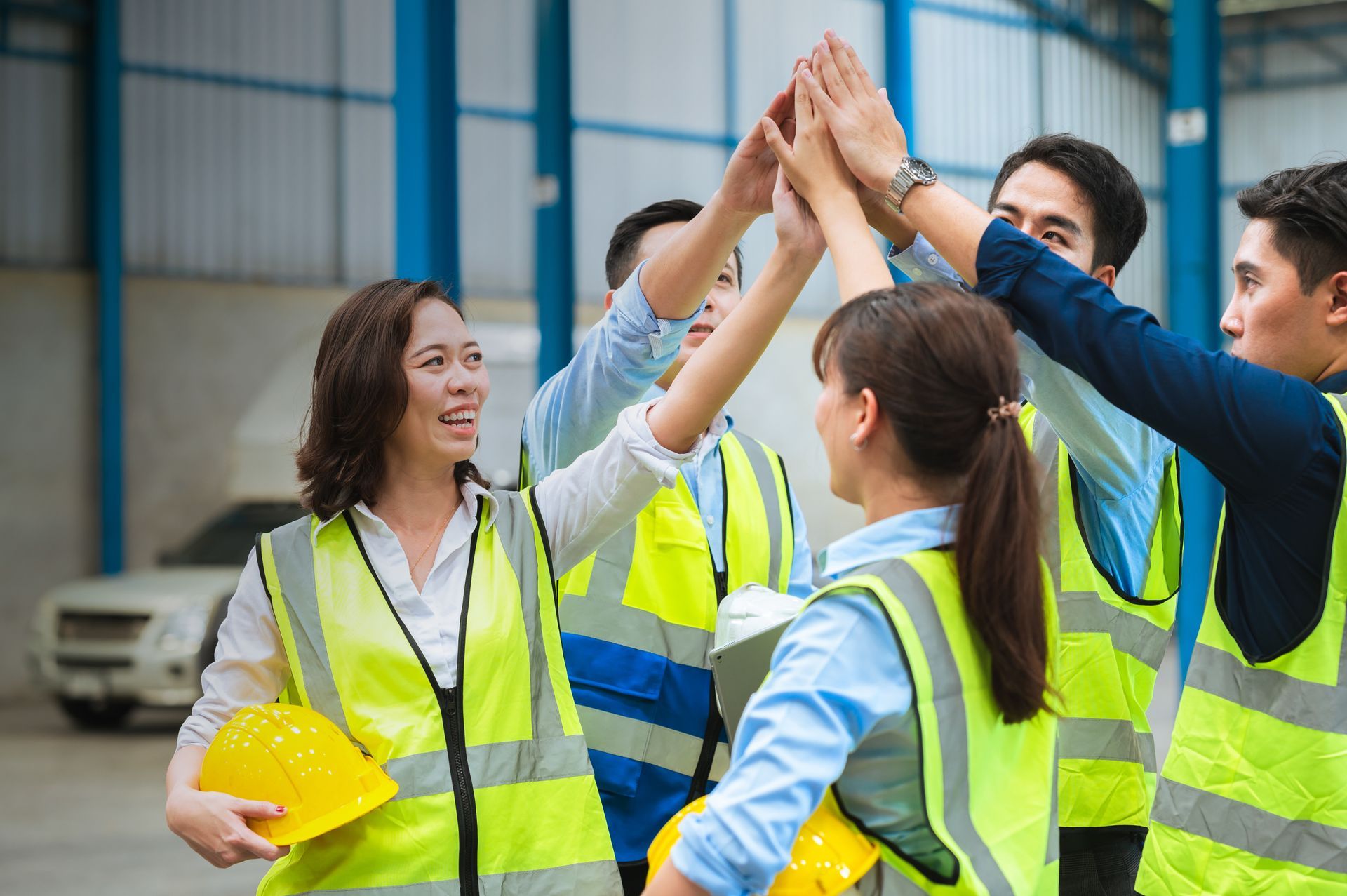A group of construction workers are giving each other a high five.