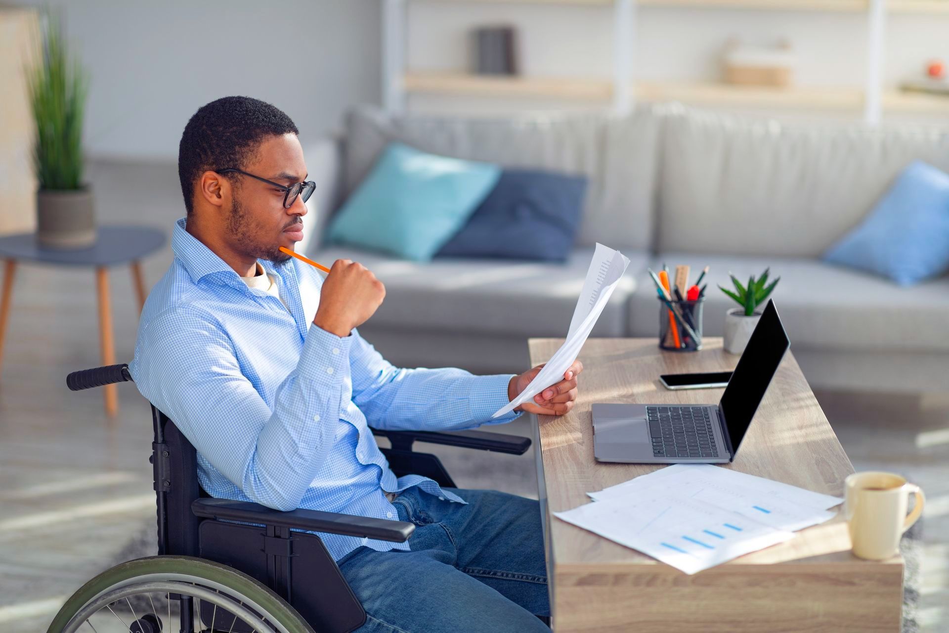 A man in a wheelchair looking at disability insurance paperwork from a disability insurance broker.