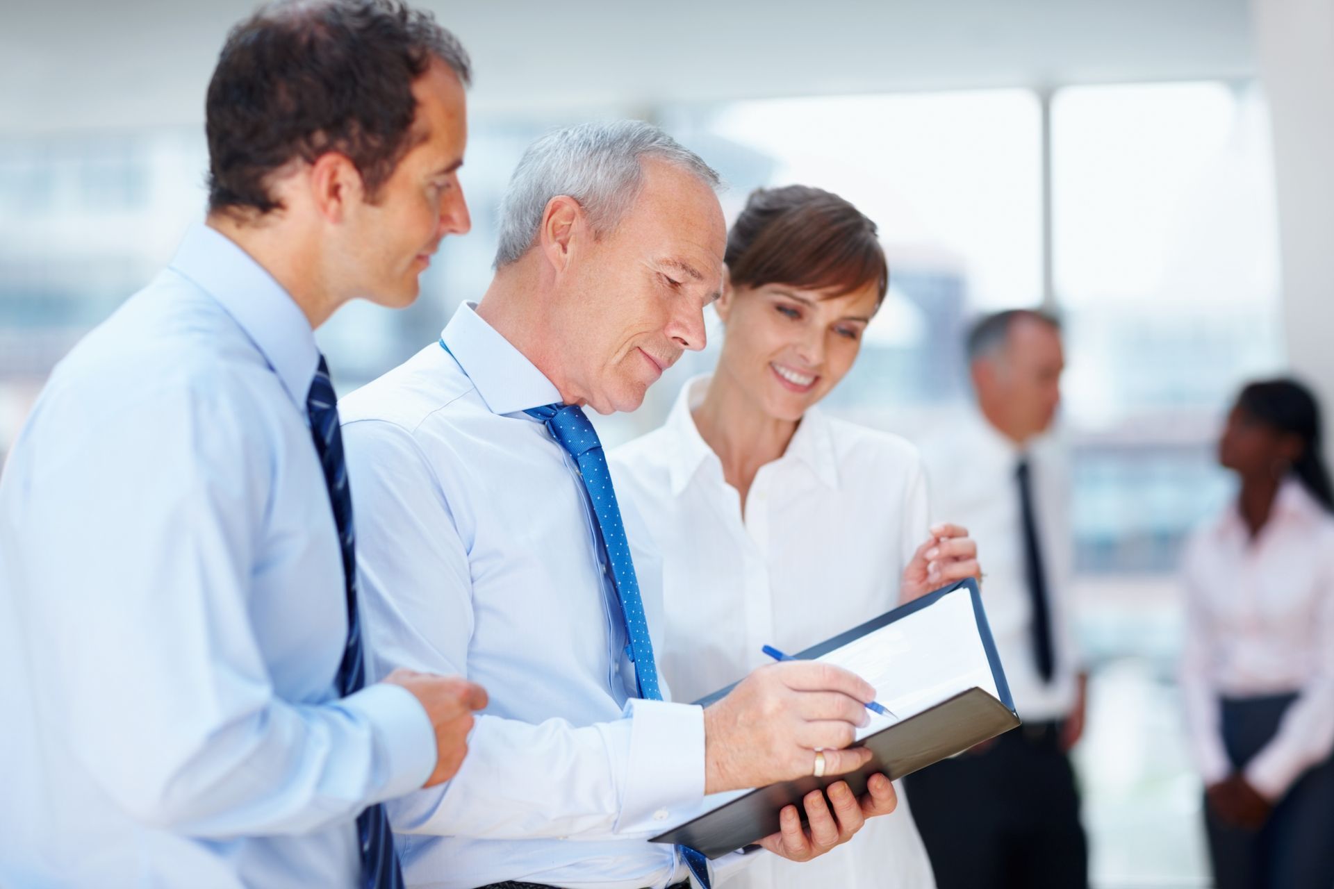 a group of business people are looking at a clipboard looking over key person life insurance options