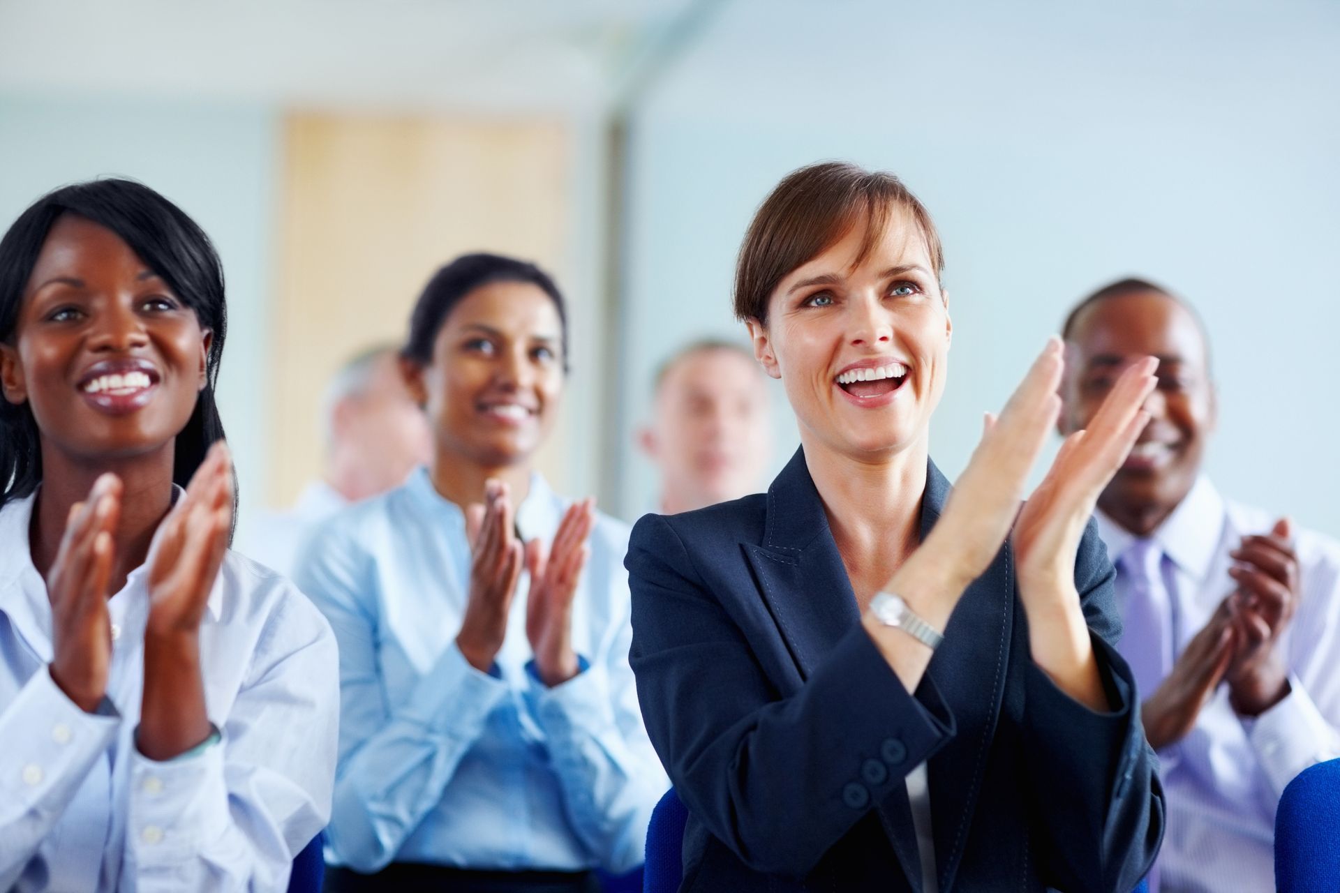 a group of people are sitting in chairs clapping their hands after a presentation on key person life insurance