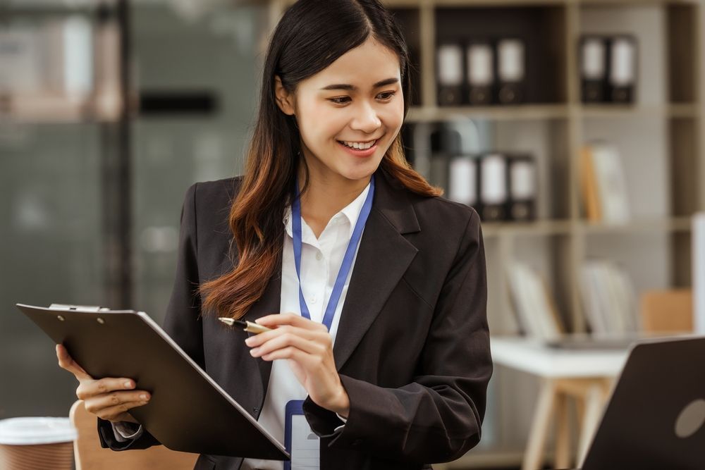 Professional woman smiling and holding a tablet in an office meeting room