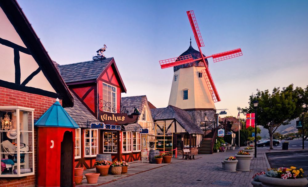 Colorful Dutch-style windmill village street with quaint shops and cobblestone walkway at sunset