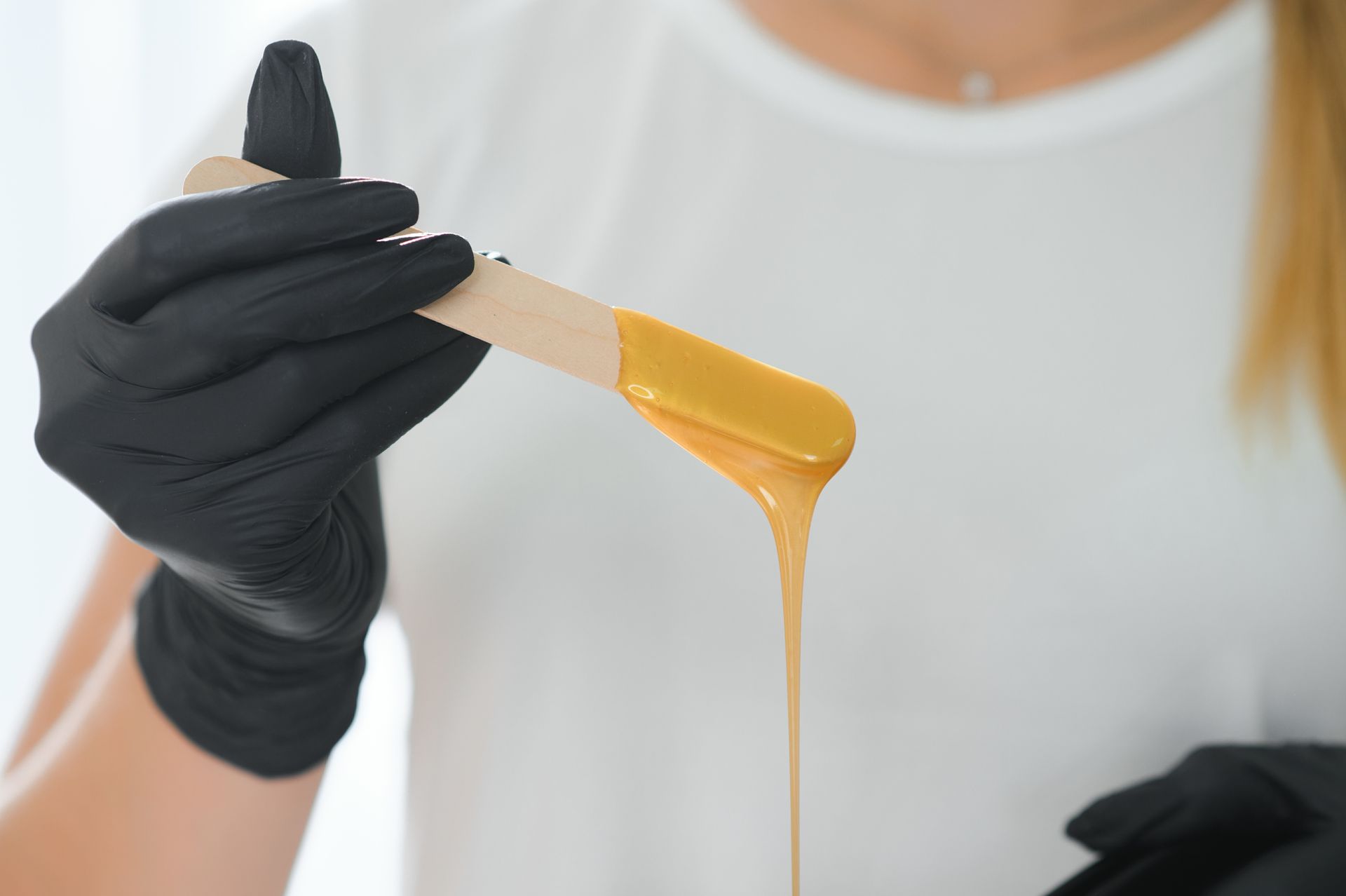 A woman is holding a stick of wax in her hand.