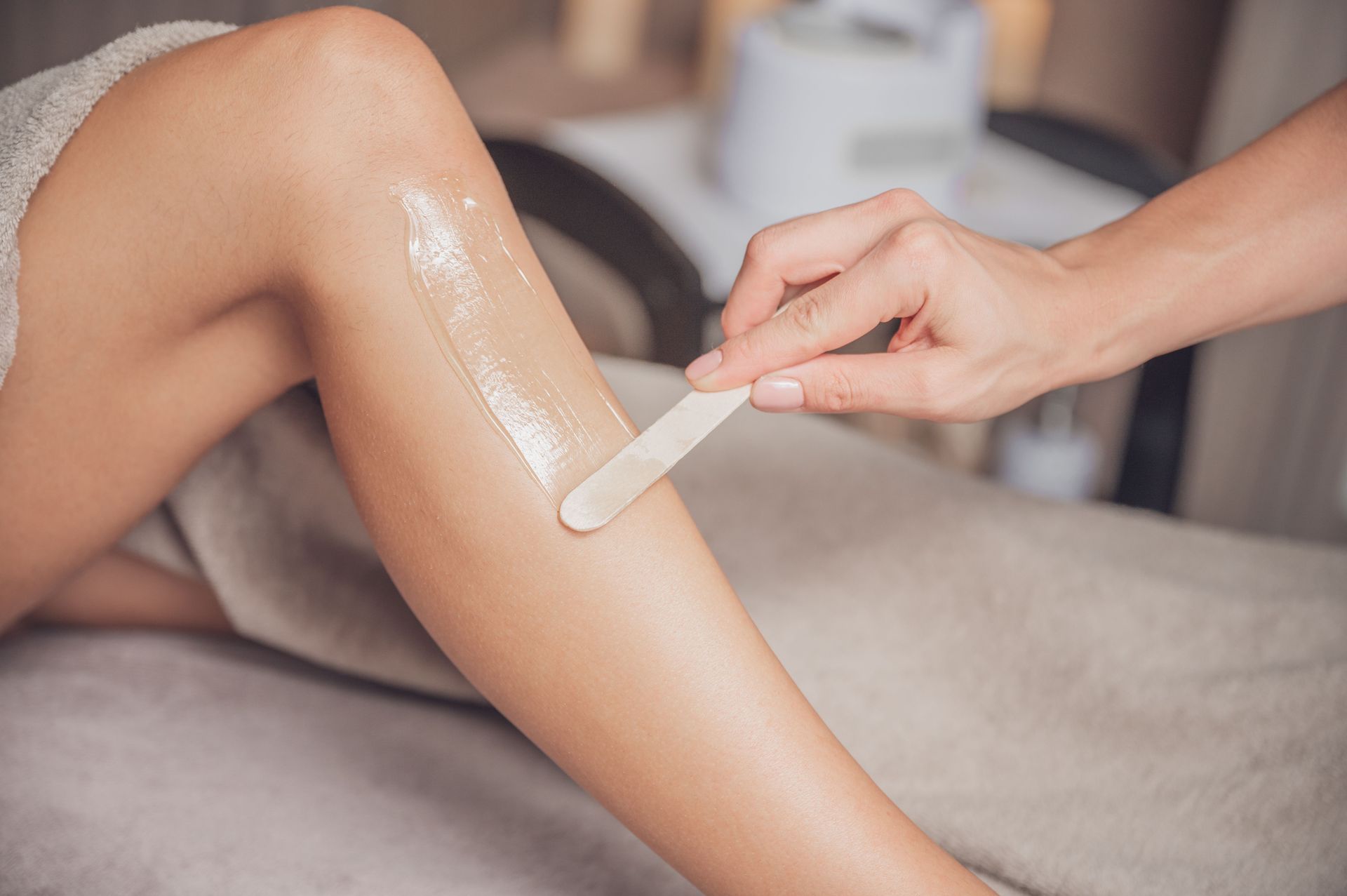 A woman is getting her legs waxed in a spa.