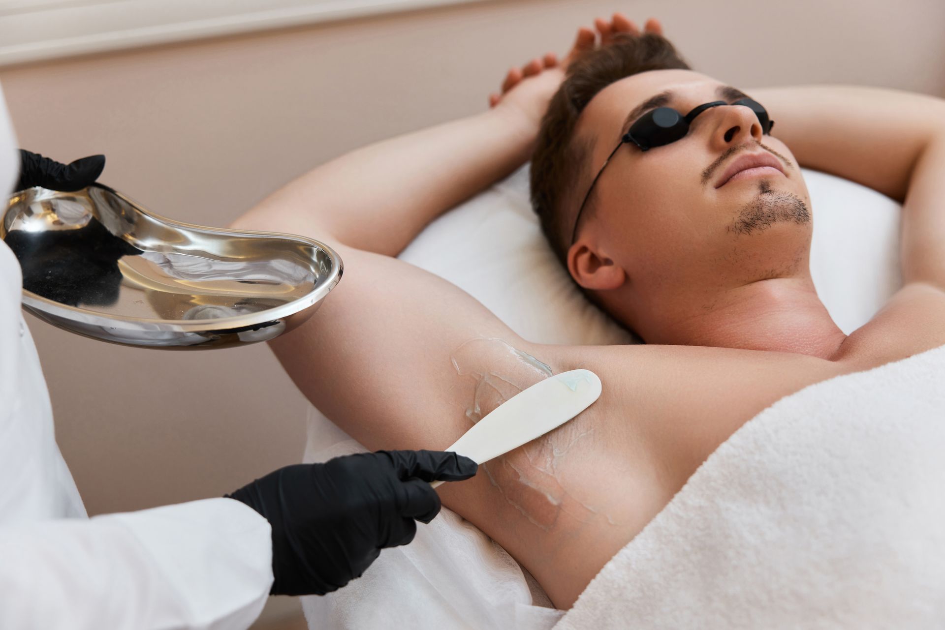 A man is getting a hair removal treatment on his armpit.