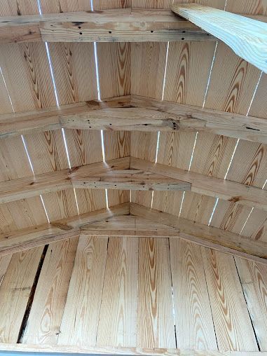 The inside of a wooden shed with a vaulted ceiling.