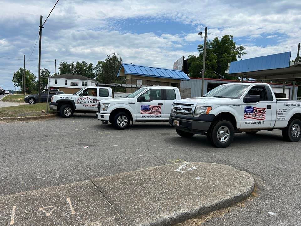Three white trucks are parked on the side of the road.