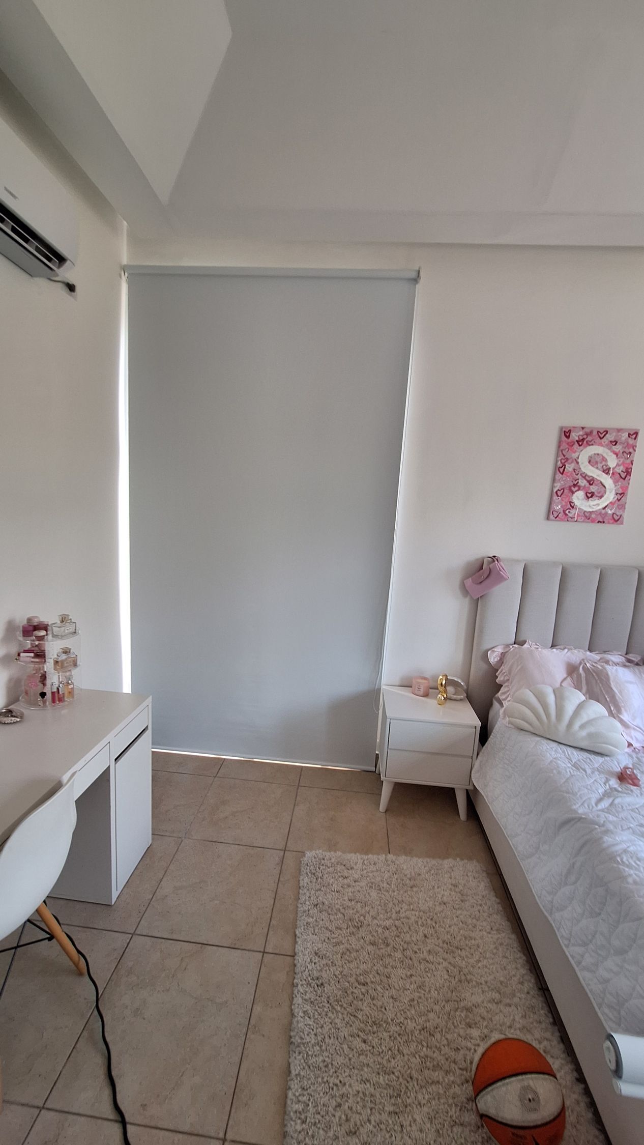 Un dormitorio de tonos claros que cuenta con un escritorio