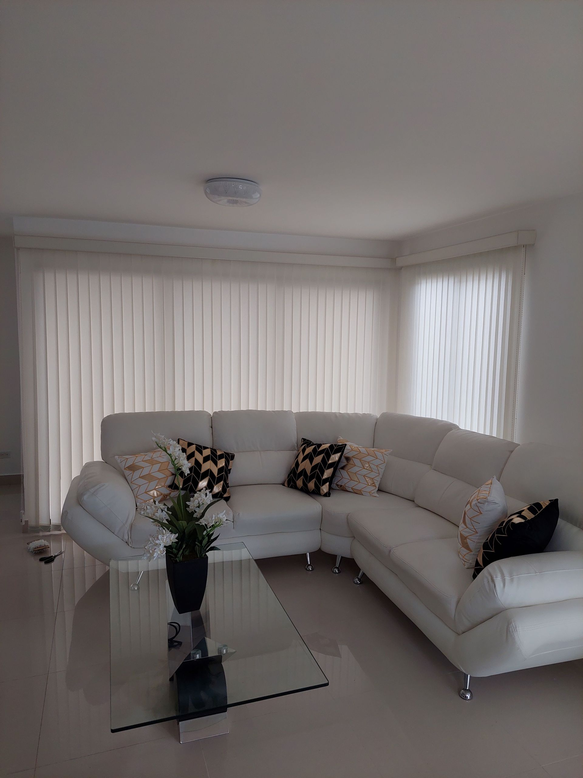 Un sofá modular blanco con cojines decorativos estampados se encuentra sobre un suelo claro