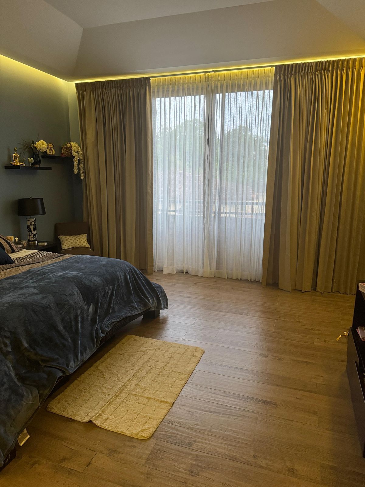 Un dormitorio con suelo de madera, una colcha azul oscuro