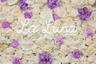 White and lavender flower wall with cursive “La Luna” text centered