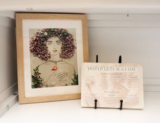 Framed floral portrait beside a small sign on a white shelf